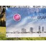 Une banderole publicitaire imprimée micro perforée mesh Tiragegrandformat est accrochée entre deux arbres