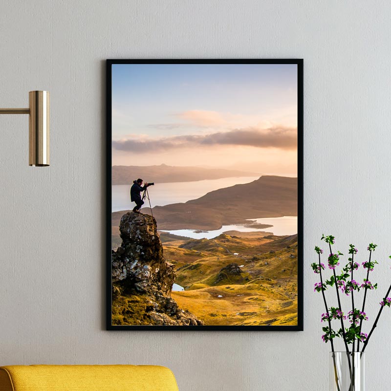 Un tirage photo représentant un photographe sur l'île de Skye est encadré dans un cadre bois 50x70 cm en bois noir et verre véritable